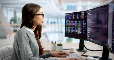 Young Female Programmer Typing Code Quickly At Her Office Desk Focused. 写真素材