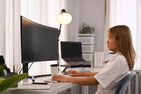 Young female programmer working with coded data on desktop computer in bright 스톡 사진