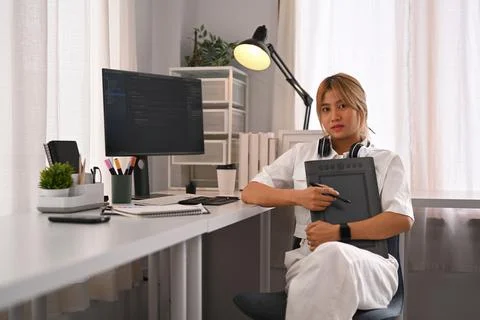 Young female programmer working with coded data on desktop computer in bright Stock Photos