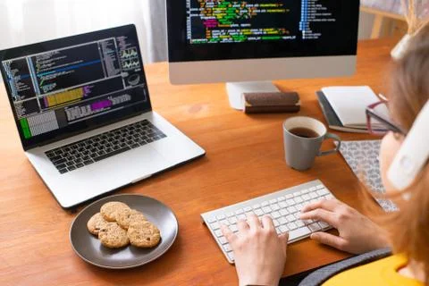 Young female programmer working with data in front of laptop and computer Stock Photos