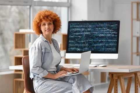 Young female programmer working with laptop and computer in office Stock Photos