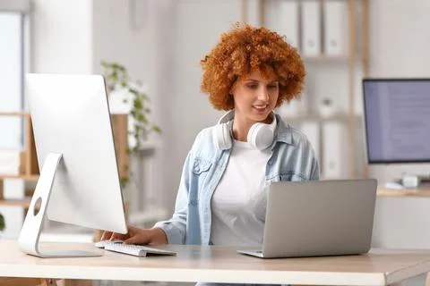Young female programmer working with laptop and computer in office Stock Photos