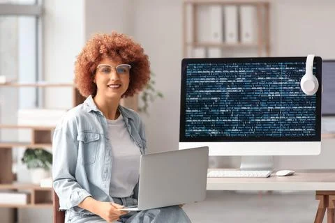 Young female programmer working with laptop and computer in office Stock Photos
