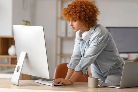 Young female programmer working with laptop and computer in office Stock Photos