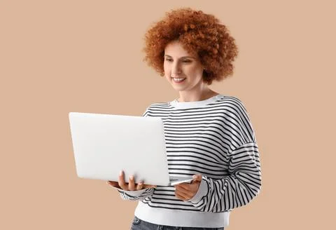 Young female programmer working with laptop on beige background Stock Photos