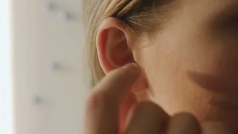 Young female pull out her hearing aid from her right ear, close up,50 fps Stock Footage 85566099