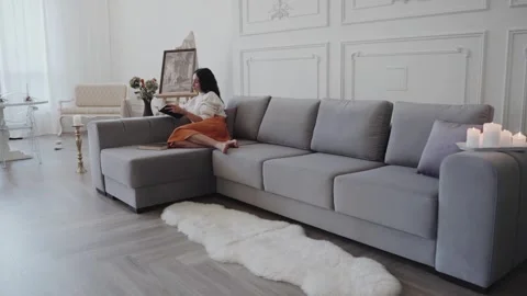 Young female reading book while sitting on couch Stock Footage 270220442