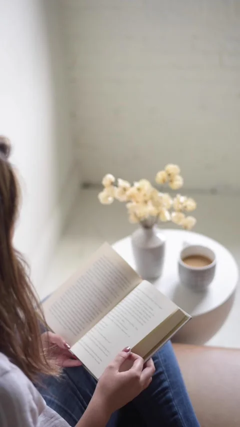 Young female reads a book while enjoying a cup of coffee Stock Footage 218267292
