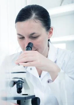 Young female researcher using microscope in the chemistry lab with laboratory Stock Photos