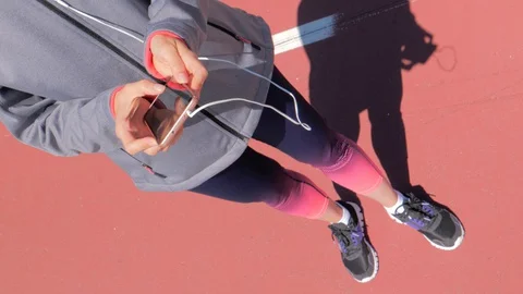 Young female runner is having break and listening to music during the run Stock Footage 129606364