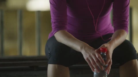 Young female runner rests for a bit and drinks some bottled water Stock Footage 51811136