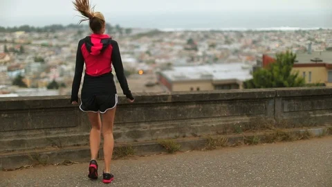 Young female runner warms up by jumping from one foot to the other on a trail Stock Footage 88438369