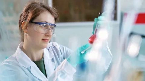 Young female scientist checking test tubes in the lab. Woman wears protective Stock Footage 85327786