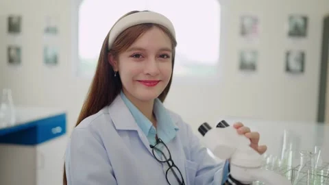 Young female scientist examines sample through microscope Stock Footage 340448716