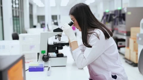 Young female scientist looking at microscope in Medical laboratory Stock Footage 131550995