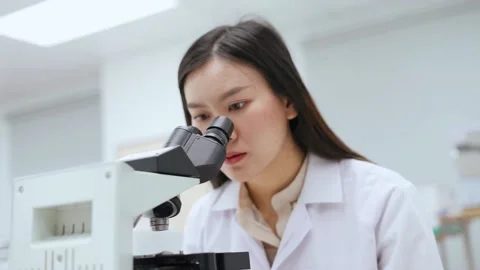Young female scientist looking at microscope in Medical laboratory Stock Footage 131550999