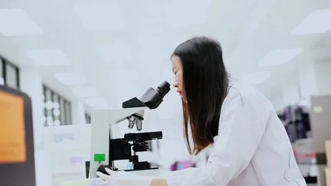Young female scientist looking at microscope in Medical laboratory Stock Footage 133444719