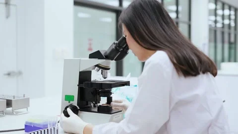Young female scientist looking at microscope in Medical laboratory Stock Footage 133444829