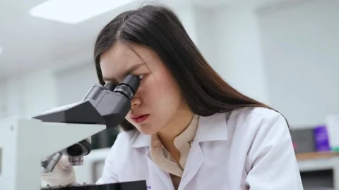 Young female scientist looking at microscope in Medical laboratory Stock Footage 133444833