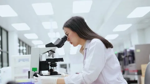Young female scientist looking at microscope in Medical laboratory Stock Footage 134057881