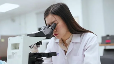 Young female scientist looking at microscope in Medical laboratory Stock Footage 134273682