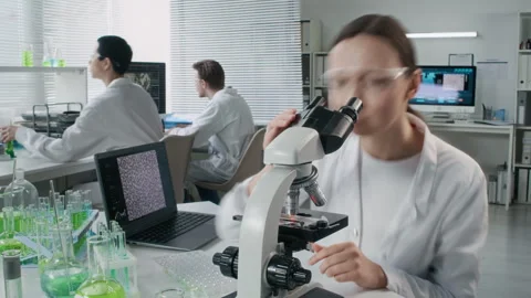 Young Female Scientist Looking in Microscope at Desk Timelapse Stock Footage 330677096