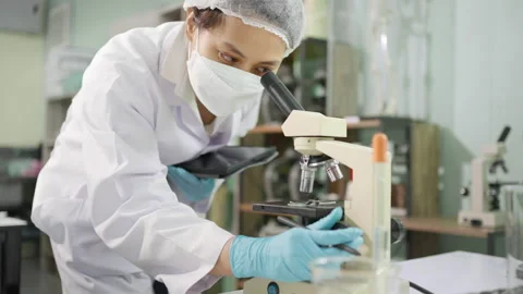 Young female scientist or lab technician working with microscope Stock Footage 201146366
