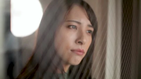 Young female sees outside through the window. Feels sad, lonley, or loss. Stock Footage 221019055
