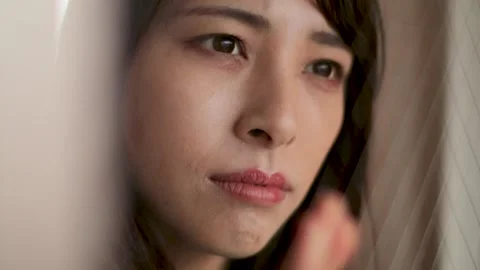 Young female sees outside through the window. Feels sad, lonley, or loss. Stock Footage 221019366