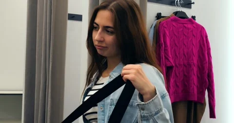 Young female shopper evaluating leopard print bag, adjusting strap while trying Stock Footage 314467914