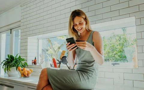 Young female smiling while making online payment with credit card Stock Photos