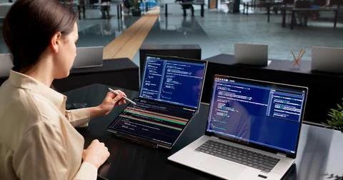 Young Female Software Developer Compares Code Changes On Dual Touchscreen Lap Stock Photos