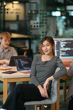 Young female software developer sitting in start up office with co working Stock Photos