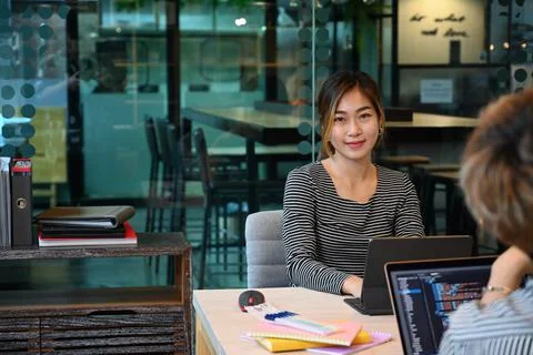 Young female software developer working in modern office with diverse colleagues Stock Photos