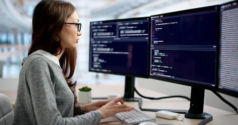 Young Female Software Engineer Coding Quickly At Her Modern Office Desk. Stock Photos
