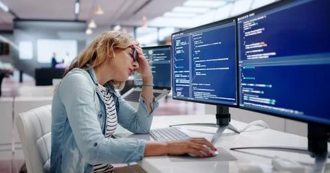 Young Female Software Engineer Works Late, Feeling Stressed And Tired. Stock-Fotos