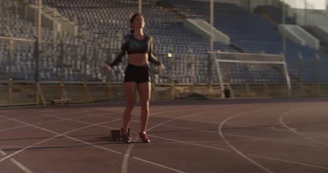 Young female sprinter preparing for run in stadium Stock Footage 243627259