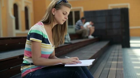 Young female student doing homework in the city, steadicam shot HD Stock Footage 12134422