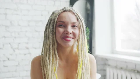 Young female student with dreadlocks smiles sincerely and waves her hand affably Stock Footage 156209704