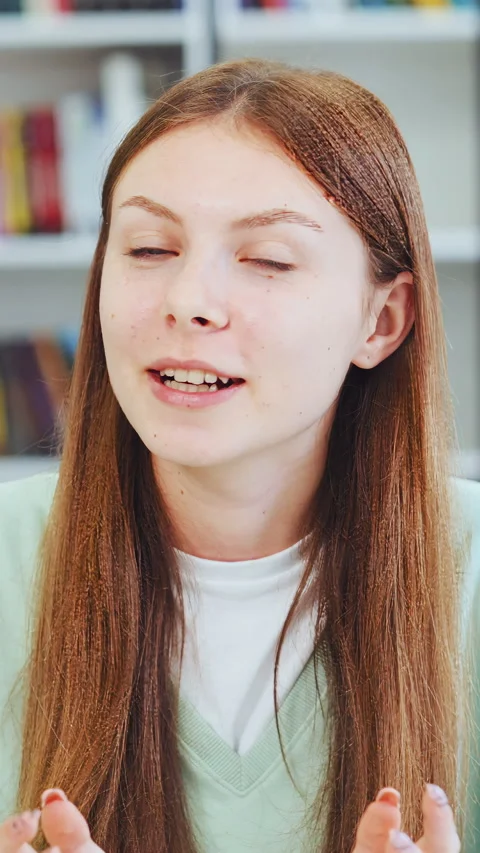 Young female student talking to camera while sitting in university library Stock Footage 334037126