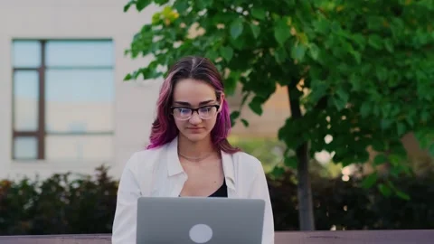 Young female student using laptop sitting on the bench in the university campus. Stockbeeldmateriaal 250434368