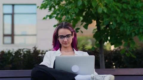 Young female student using laptop sitting on the bench in the university campus. Stock-Footage 261783680