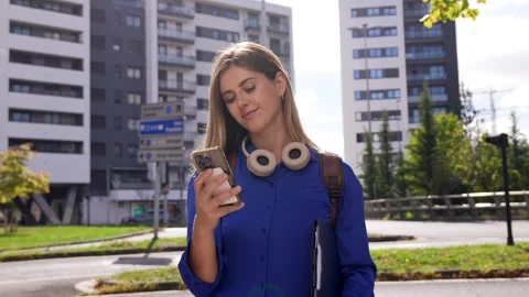 Young female student using smartphone walking in the city Stock Footage 346449238