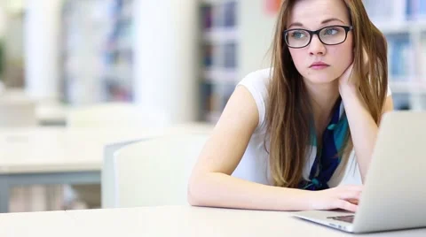 Young female student working alone in a campus library Stock Footage 50348936