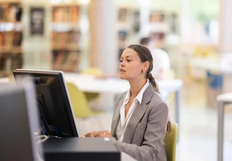 Young female student working on computer in library Stock Photos