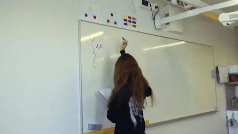 Young female student writing a math formula on a whiteboard Stock Footage 345188807