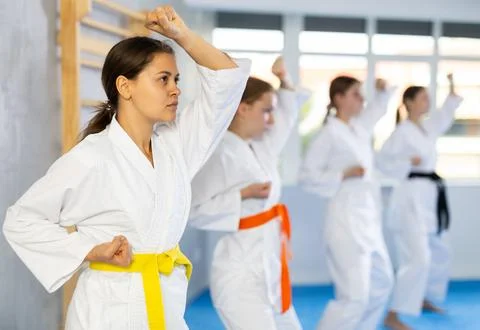 Young female students repeat position and perform sequence of punches and Stock Photos