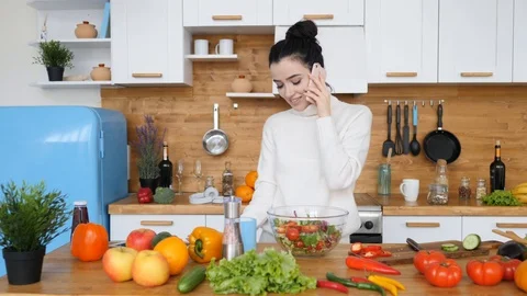 Young Female Talking On Cellphone While Cooking Healthy Food In Kitchen At Home. Stock Footage 105300942