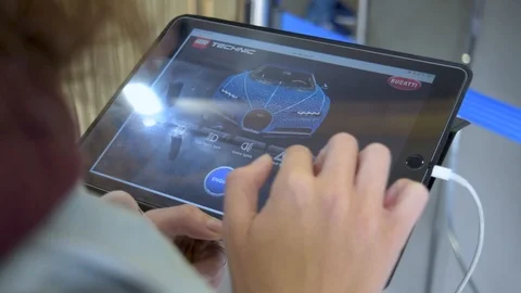 Young female tap remote control buttons on ipad at Lego Bugatti Chiron display Stock Footage 114007668