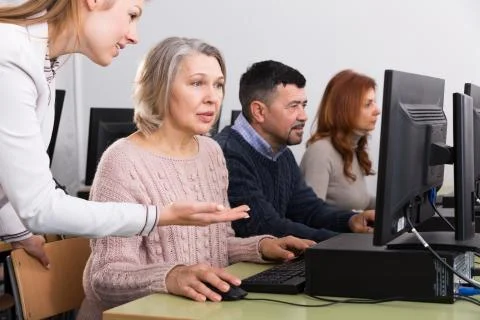 Young female teacher explaining computer skills to mature woman Fotos de archivo